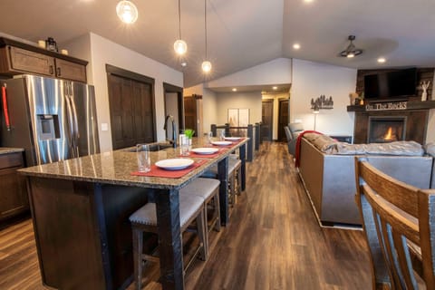 Prepare gourmet meals in the sleek kitchen at "On The Rocks," featuring a powerful gas stove, stainless steel appliances, and a spacious granite island with bar stools.