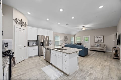 Bright open-concept kitchen and living area with granite island, stainless steel appliances, and easy flow for groups