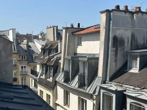 Old Paris rooftops in view; serene street with minimal traffic below.

