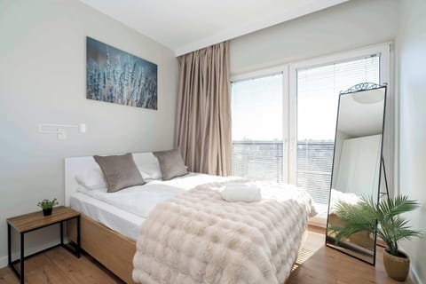 A bright bedroom with a large window and cozy textiles invites you to restful sleep and sunlit mornings.