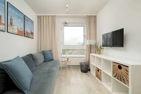 A bright living room with a sofa bed from which you can watch your favourite programmes on the flat-screen TV hanging on the wall.
