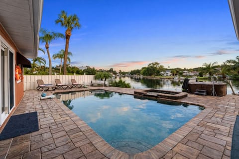 waterfront pool side retreat overlooking the canal, palm trees frame the view.