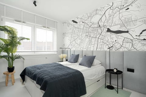 A spacious bedroom featuring a comfortable double bed, large windows letting in natural light, and elegant modern decor with soft tones.