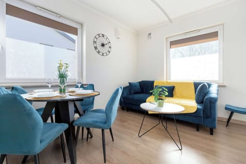 A cozy living room with blue and yellow accents, featuring a dining table and a large window.