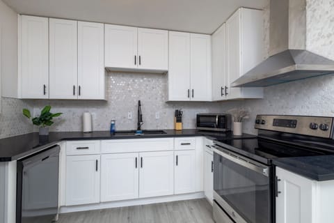 Fully stocked kitchen with a stainless steel range hood and cooking essentials.