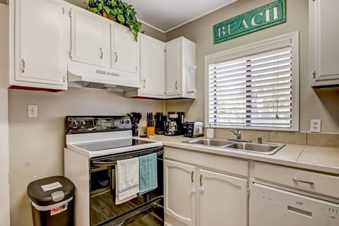 Bright, well-equipped kitchen with white cabinets and beachy green accents.