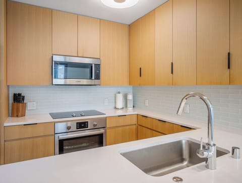 Kitchen - Create meals with ease in a modern kitchen accented by a striking blue tile backsplash, stainless appliances, and bright counters that reflect Honolulu’s fresh, vibrant energy.