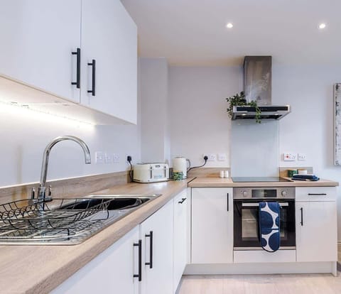 Modern kitchen equipped with a stovetop, microwave, toaster, and kettle—everything you need for a quick meal or morning coffee.