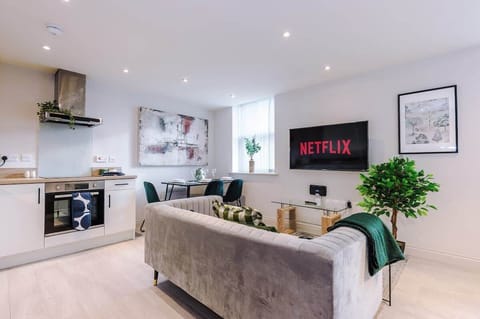 Bright living room with a comfy sofa, smart TV with Netflix, and large windows. Includes 2 fold-out chair beds that convert into single beds, offering extra sleeping space for up to 2 guests. Stylish wall art adds a modern touch.