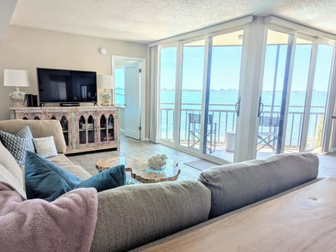 View of living room from entrance, with bay views and private screened balcony.