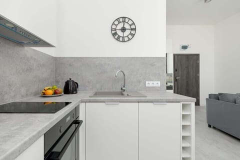 Compact kitchen area with white cabinets, a black backsplash, and essential appliances.