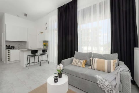 A unique studio apartment with a modern grey sofa, wall-mounted TV and minimalist décor.