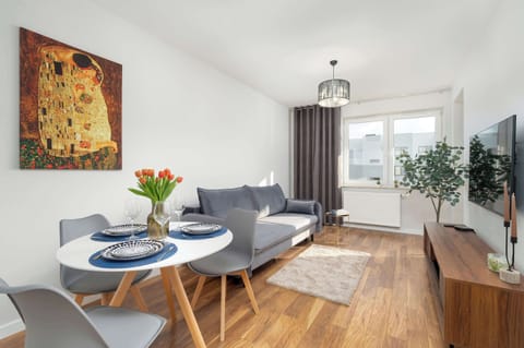 This bright and spacious living room with wooden flooring, grey furniture, and colorful accents is the perfect place to relax.