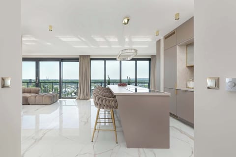 The stylish kitchenette connected to the dining room offers a modern kitchen island, high bar chairs and appliances such as an induction cooktop, oven and bean coffee maker.