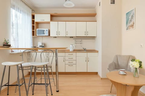A spacious kitchenette with a large window letting in plenty of natural light and elegant white kitchen furniture provides a bright and pleasant atmosphere.