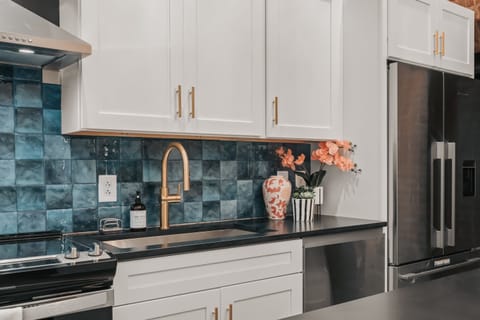 The kitchen features sleek stainless steel appliances, crisp white modern cabinetry, and a bold, colorful backsplash that adds a vibrant pop to the space.