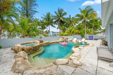 Relax by a stunning pool surrounded by palm trees and lush greenery, complete with a gentle waterfall and a playful flamingo float—your private tropical getaway awaits.