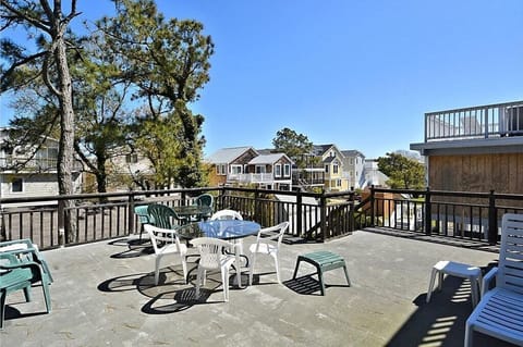 A spacious rooftop deck is equipped with a dining table and several chairs, surrounded by trees, perfect for enjoying the fresh air.