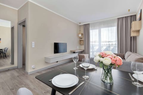 An elegant living room with a large, bright window, a comfortable upholstered sofa, and a stylish coffee table decorated with fresh flowers creates a pleasant space for relaxation.