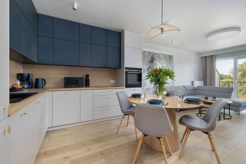 A contemporary kitchen and dining setup with navy blue and white cabinetry and stylish wooden accents.