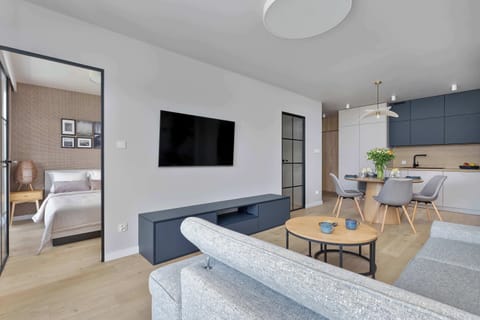 Another perspective of the open-plan lounge area with a TV, large windows, and sleek modern design.