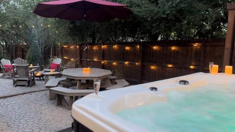 Hot tub, picnic table, fire pit with wood provided at dusk. Gas grill to left.