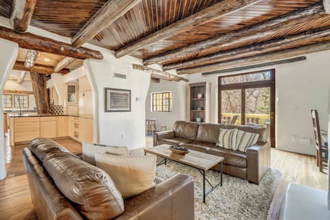 Welcome to Adobe del Sur! Take a peek into our kitchen, where even the live tree trunk seems to be enjoying the view of our cozy living room—just don't ask it for decorating tips!