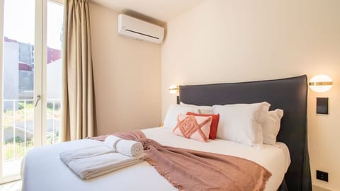 Peaceful bedroom with soft tones, quality linens, and balcony light—complete with air conditioning for year-round comfort. #RestWell #CozyRetreat #LovelyStay