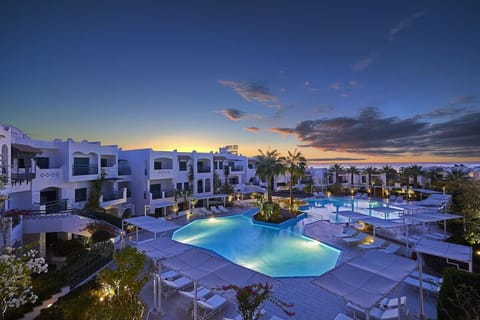 Unwind at sunset beside glowing lagoon pools and palms.