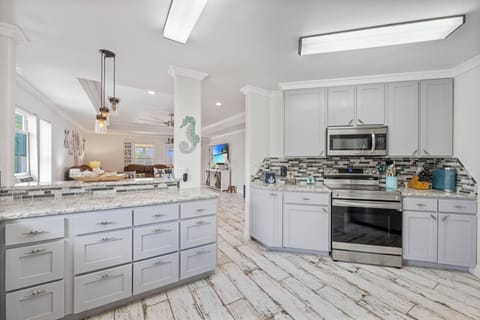 Inviting Coastal Kitchen Overlooking Bright, Social Living and Dining Spaces