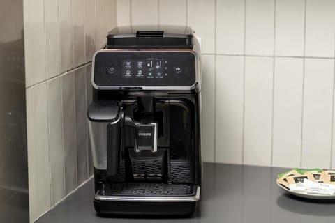 Black coffee machine on a white tile backsplash.