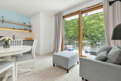 LivinOpen kitchen and dining space with blue cabinets and modern appliances.g room with grey sofa and access to the balcony.