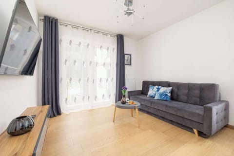 Bright living room with a large TV and comfy seating.