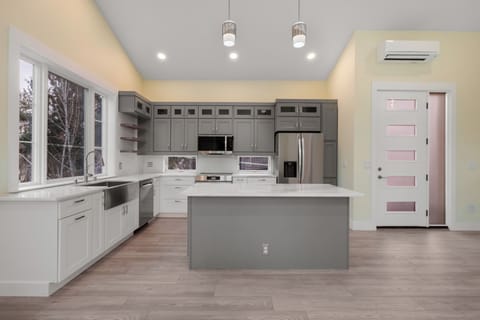 Kitchen with island. Front door. Windows overlooking tree-lined alley below. 