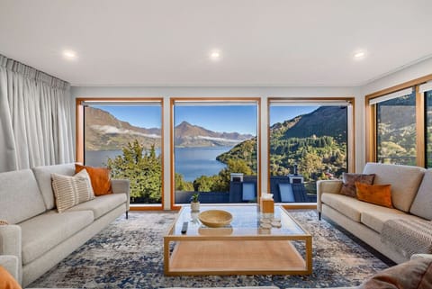 Glass-fronted lounge with roaring wood fire and Walter Peak glowing in the distance