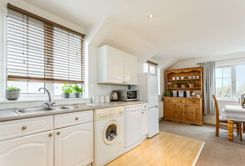 Arnold Cottage in Treyarnon Bay. Open kitchen area with dishwasher, washing machine/dryer and fridgeâ€‘freezer