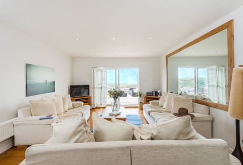 Surfside, Mawgan Porth Newquay: First floor: A gorgeous, bright, and airy living area overlooking stunning coastal views, with the sound of crashing waves in the background. Spacious patio doors open onto the patio, letting you step outside and breathe in