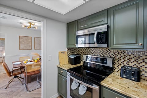 This open kitchen blends style and function with its black appliances, gorgeous countertops, and thoughtful layout that connects seamlessly to the game room.