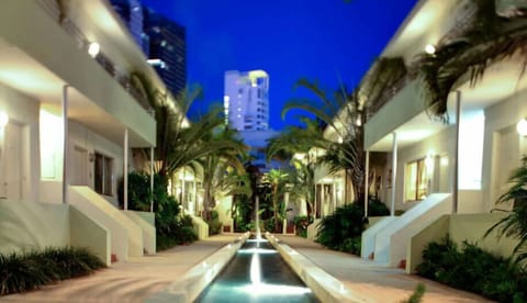 Wander past a serene water feature between stylish buildings.
