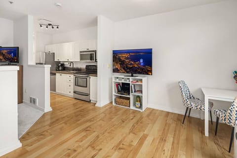 Modern kitchen with stainless steel appliances, white cabinetry, and a cozy dining nook with seating for two.