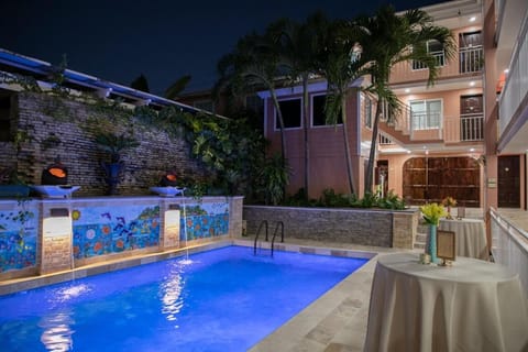 Sip and swim under evening lights in a glowing pool.