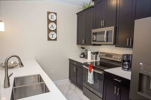 Whip up delicious meals in this contemporary kitchen featuring stainless steel appliances, dark shaker cabinets, quartz countertops and subway-tile backsplash - a chef's dream awaits!