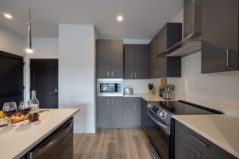 Unit 1: Fully equipped kitchen stocked with your basic cooking essentials. Includes stainless steel appliances, small kitchen island, coffee machine, and toaster.