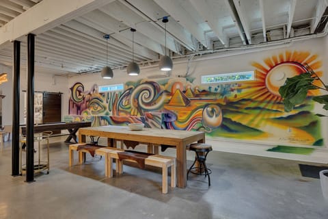Striking full-wall mural featuring vibrant, surreal artwork with pyramids, swirling patterns, and a rising sun