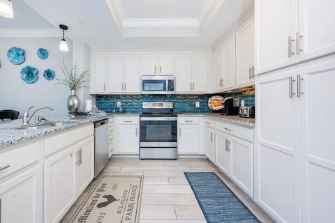 Prepare meals in this stylish kitchen with sleek cabinetry, stainless appliances, and teal backsplash