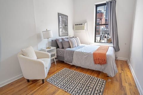 Bright, stylish room with full bed, chair, and city views