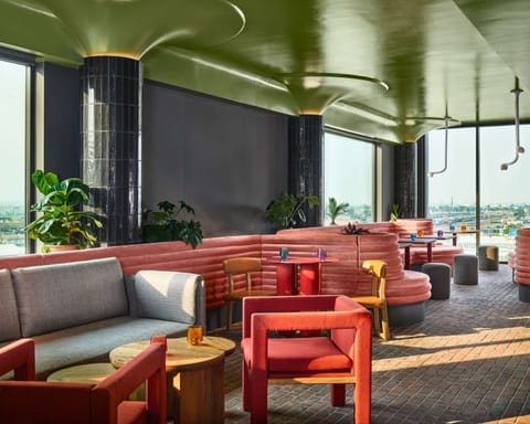 Rooftop lounge with pink booths, soft chairs, and big windows
