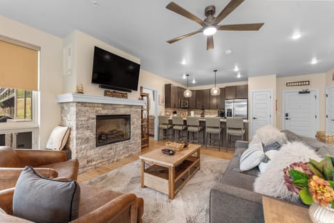 Unwind in your open-concept living space where modern comfort meets rustic charm with a cozy fireplace and stylish kitchen.