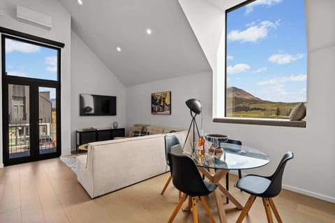 Spacious lounge and dining area with vaulted ceilings, with a window framing the natural sceneries so effortlessly
