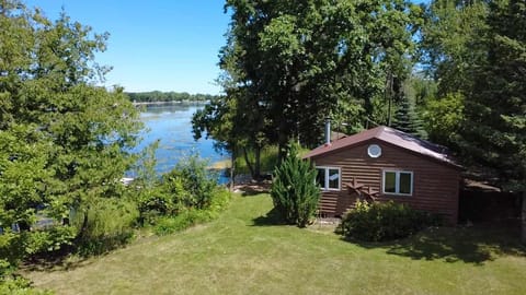 Aerial view showcasing the charming waterfront cottage nestled along Little Sturgeon Bay. Enjoy sweeping views of the bay, private shoreline access, and a tranquil setting perfect for kayaking, fishing, or simply relaxing by the water.